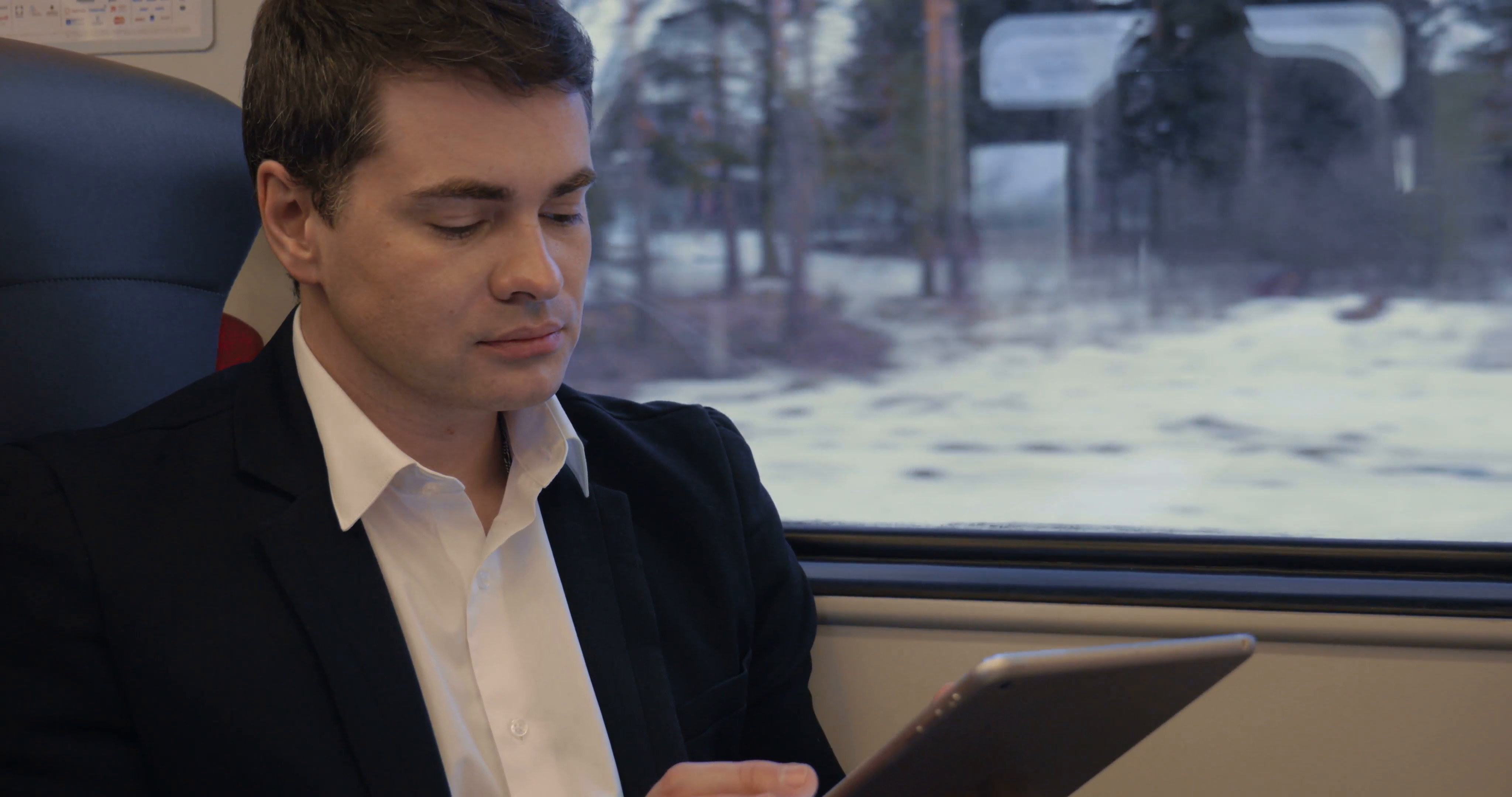 A man in the train watching movies on his tablet